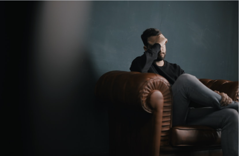A man sitting on a couch with his head in his hand